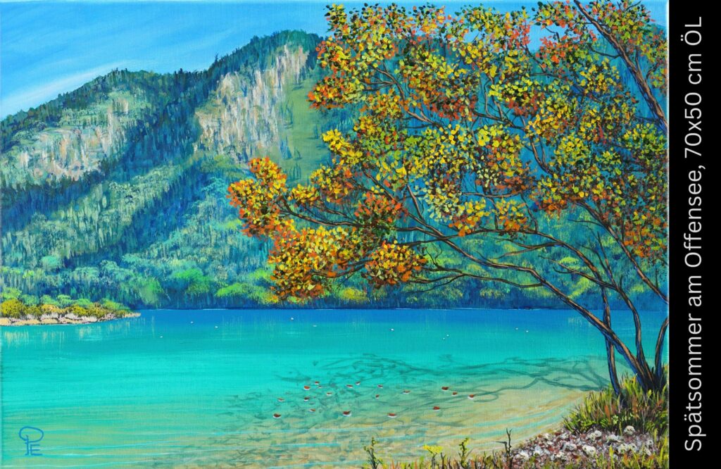 Herbstbaum mit goldgelben Blättern an türkisblauem Bergsee mit Kieselstrand und bewaldeten Bergen im Hintergrund